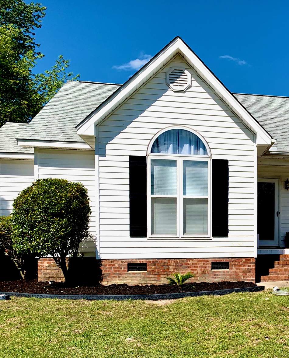 A home with vinyl siding, a shingle roof and an arched replacement window